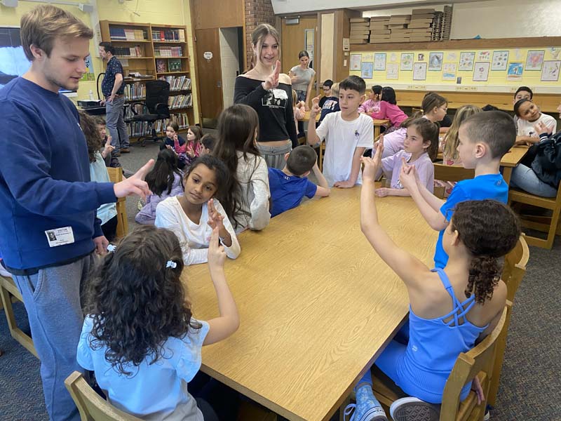 High School students doing sign language with elementary school students