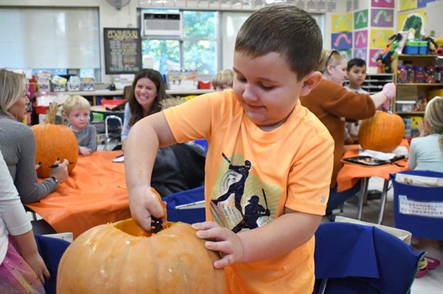 student scooping out a pumpkin