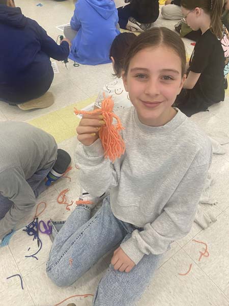 Student holding yarn doll