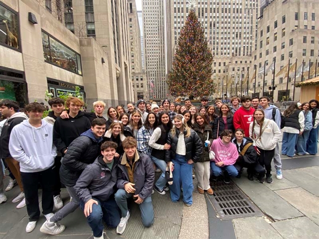 Students smiling for picture in front of the tree in NYC