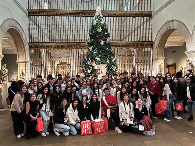 Students smiling for picture in front of the tree in the museum