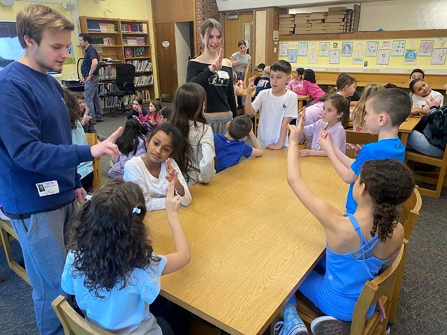 High School students doing sign language with elementary school students