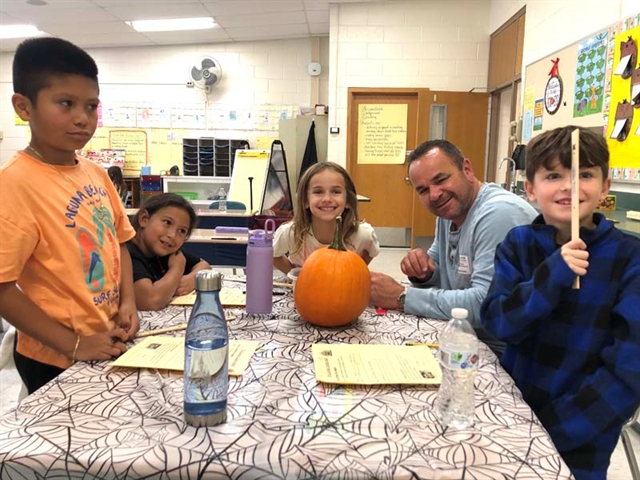 Students and parents carving out pumpkins