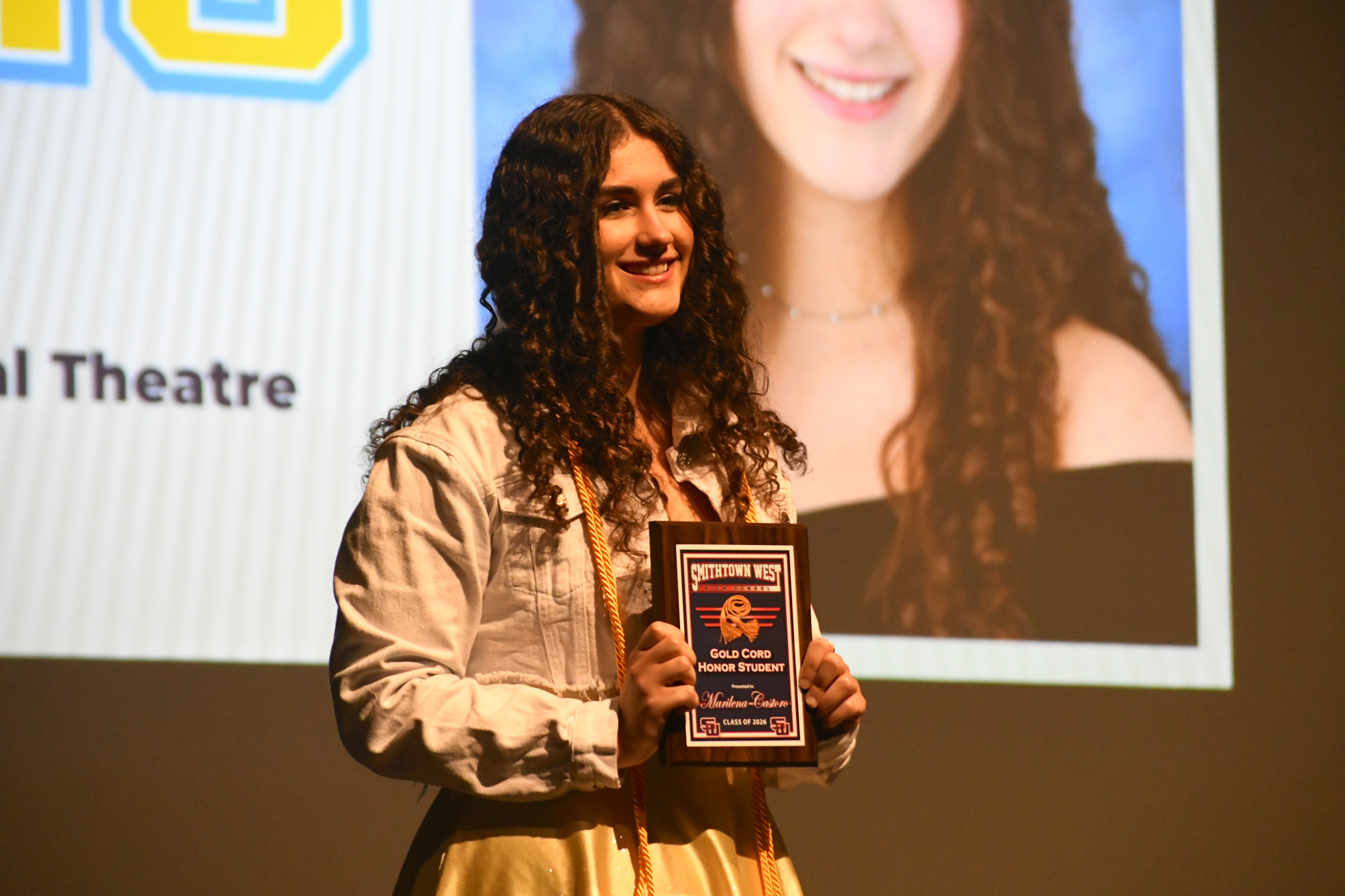 Student smiling holding plaque