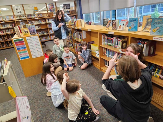 High School students doing sign language with elementary school students