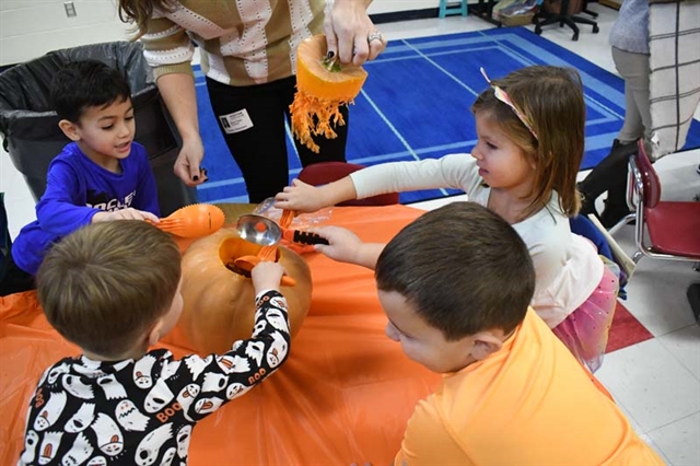 students scooping out a pumpkin