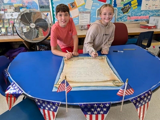 Students smiling in classroom in front of class rules