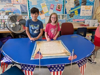 Students smiling in classroom in front of class rules