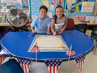 Students smiling in classroom in front of class rules