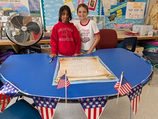 Students smiling in classroom in front of class rules