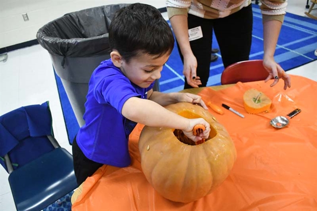 student scooping out a pumpkin