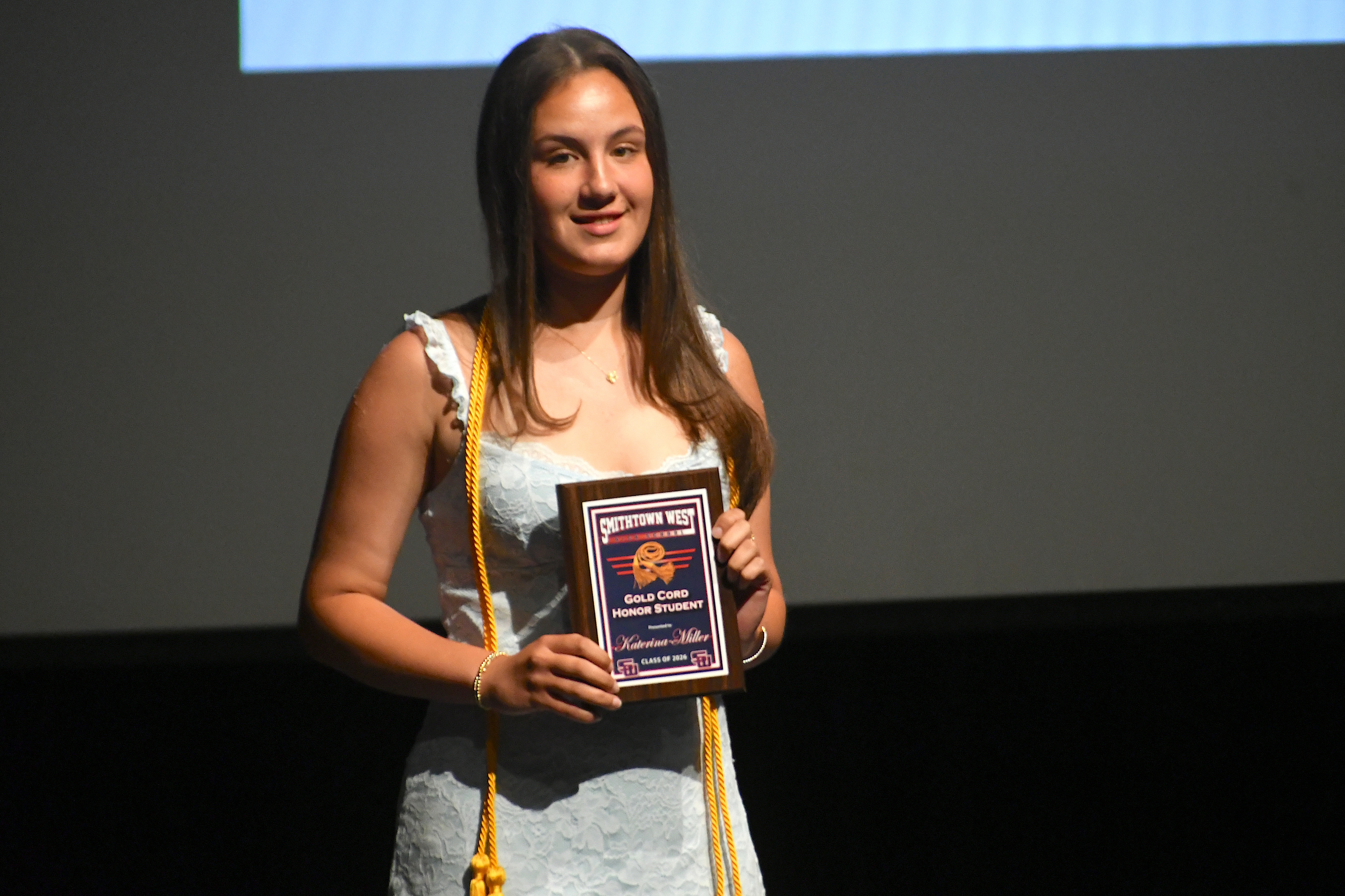 Student smiling holding plaque