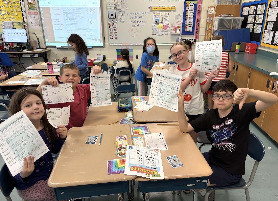 children in classroom holding work