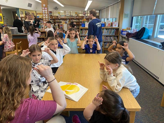 High School students doing sign language with elementary school students