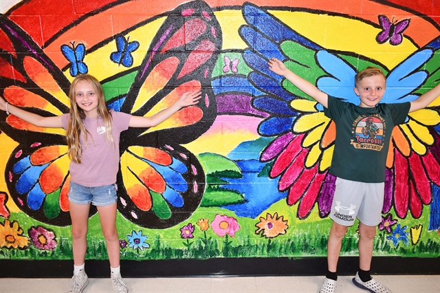 students standing in front of a mural