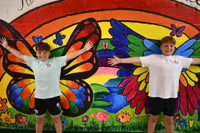 students standing in front of a mural