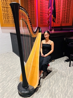 student smiling next to instrument
