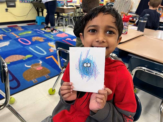 student holding scribble art