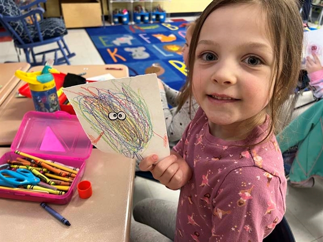 student holding scribble art