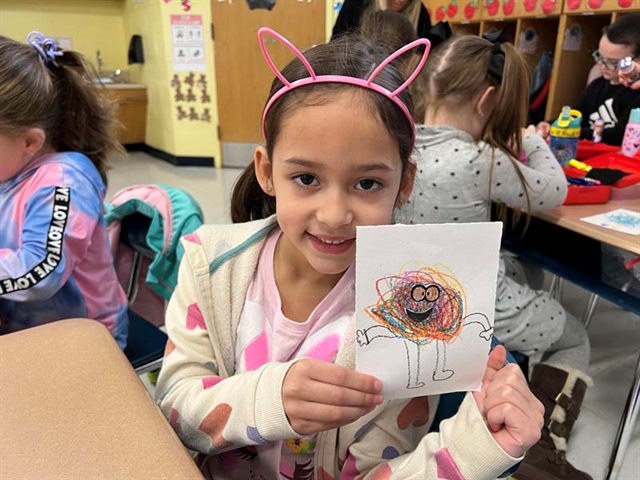 student holding scribble art