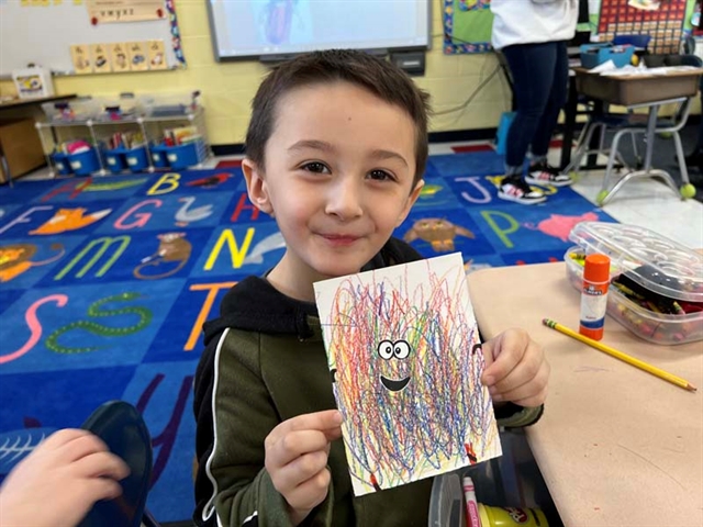 student holding scribble art