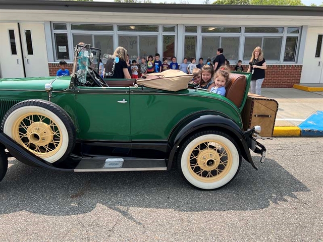 students posing by an old car