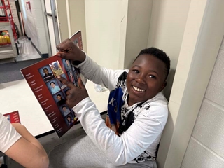 Student smiling looking at yearbook