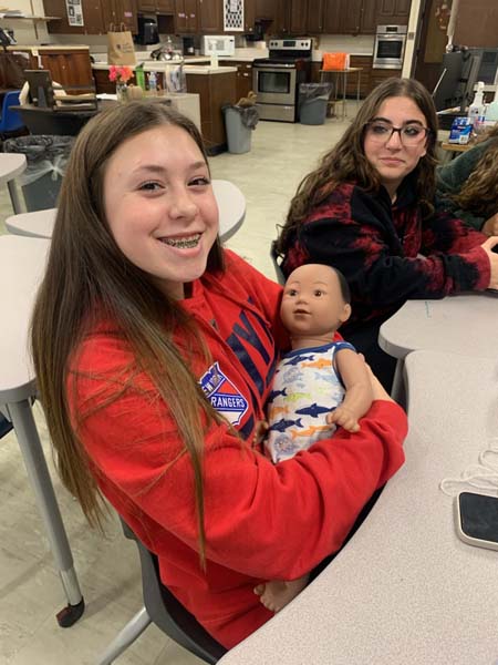 High School student holding a computerized baby