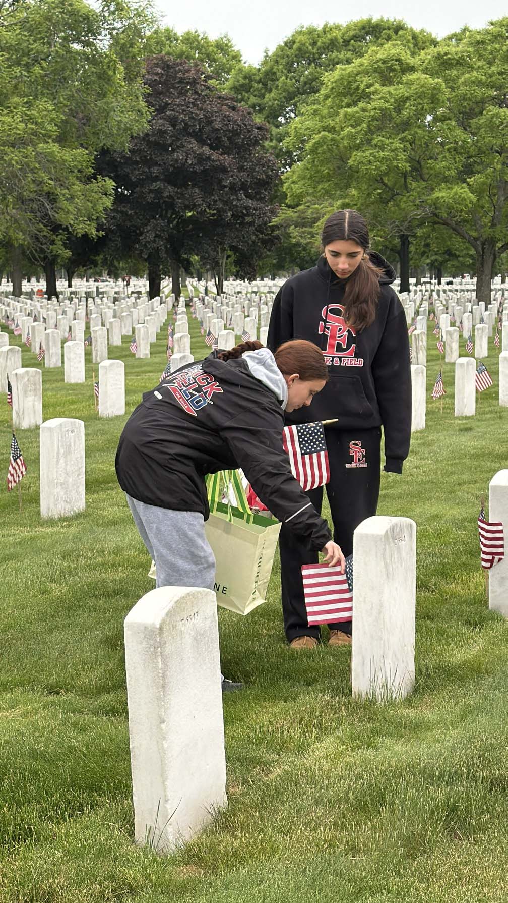 students placing flags on tombstone