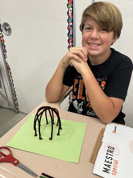 Student posing for picture with wigwams