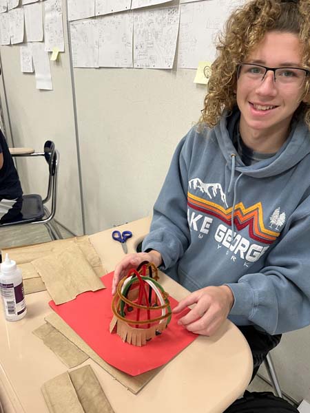 Student posing for picture with wigwams