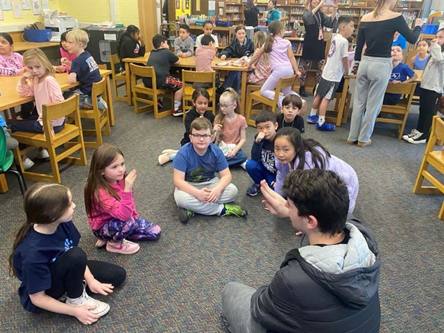 High School students doing sign language with elementary school students