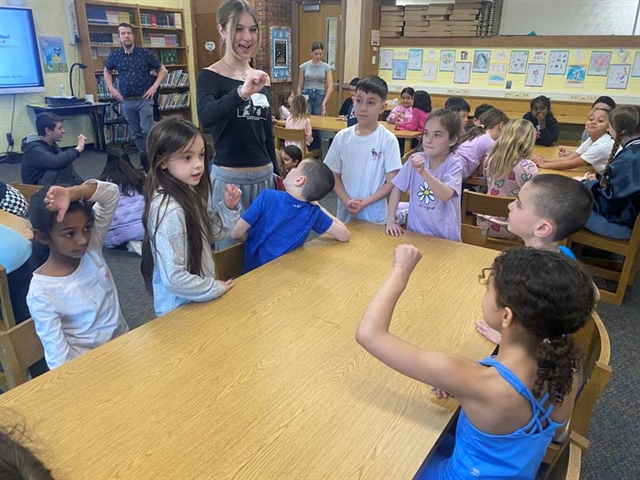 High School students doing sign language with elementary school students