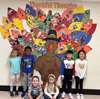 Students posing in front of cutout Turkey which they designed