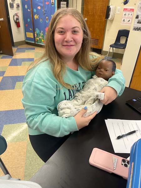 High School student holding a computerized baby