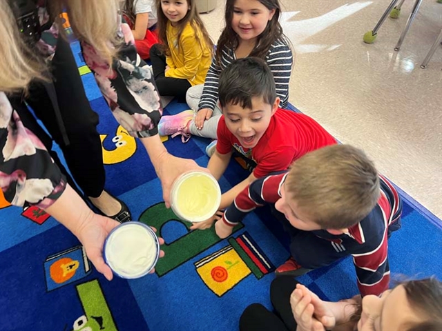 Students churning butter smiling