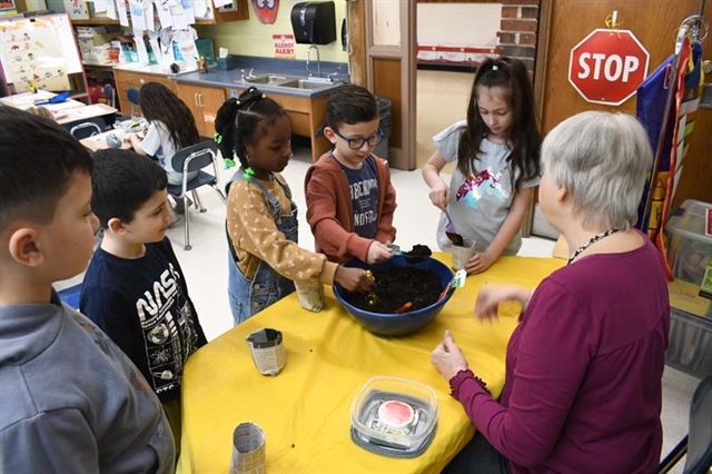 Students putting soil in plant holder