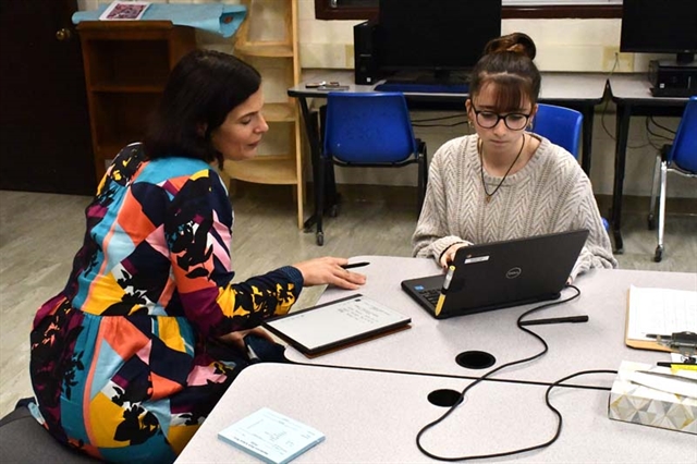 Student sitting with teacher at writing center