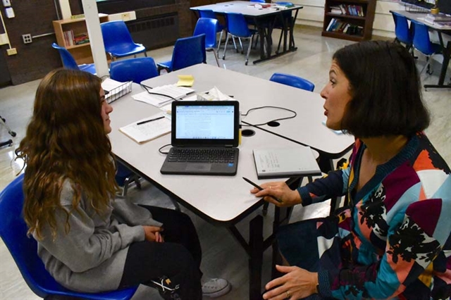 Student sitting with teacher at writing center