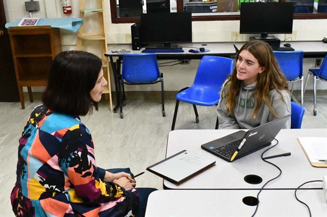 Student sitting with teacher at writing center