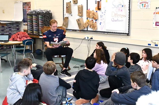 football player reading to students