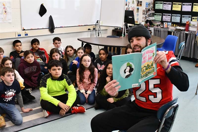 football player reading to students