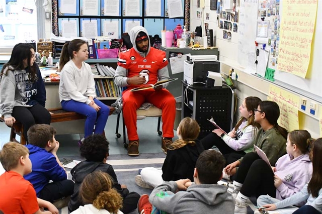 football player reading to students