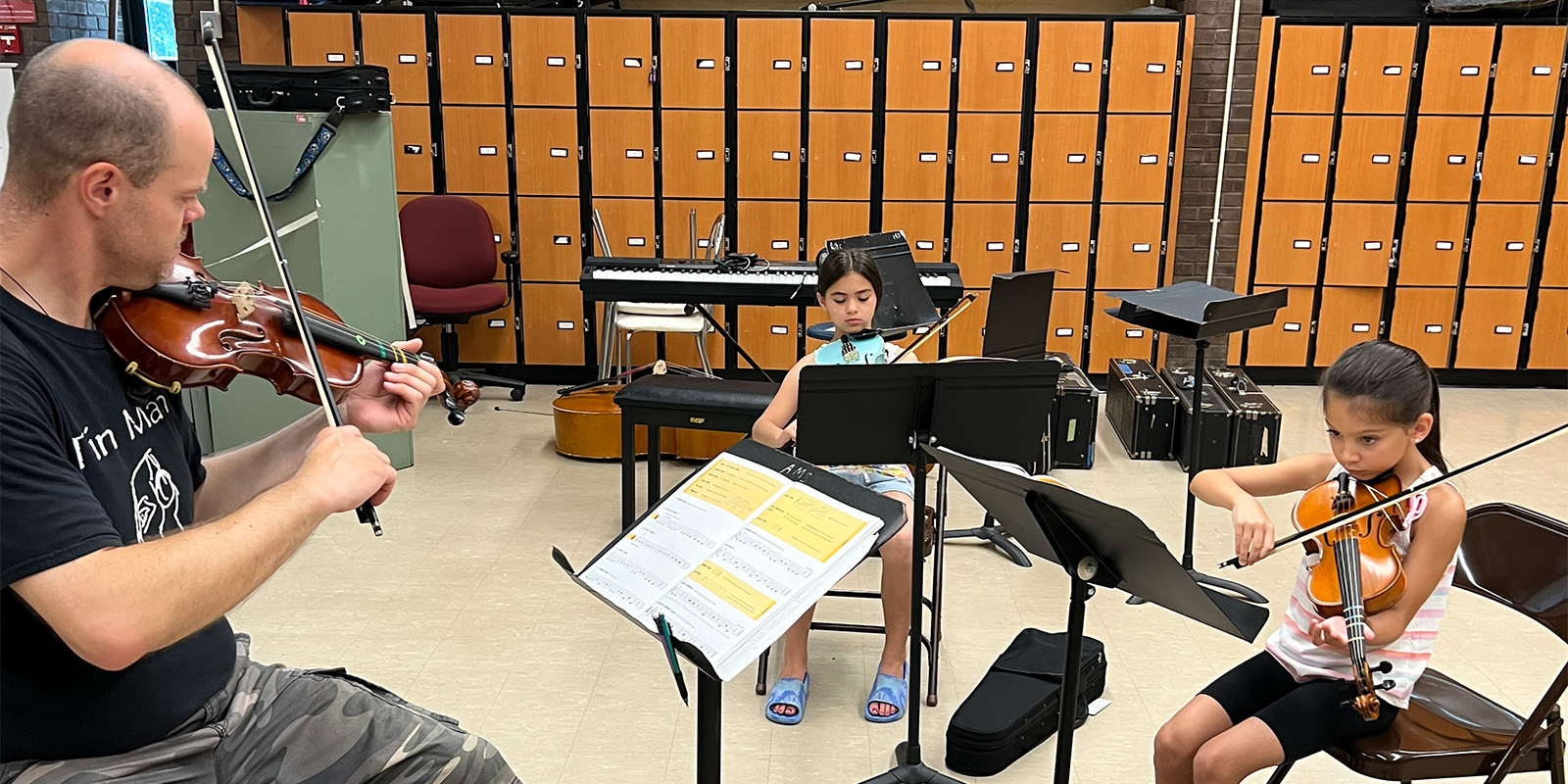 Instructor and two students playing violin