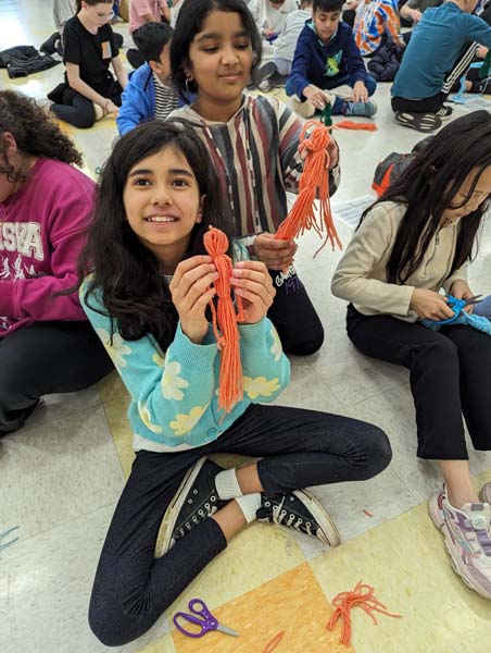 student holding yarn doll