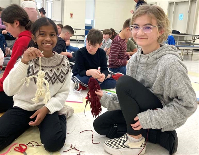 students with yarn dolls
