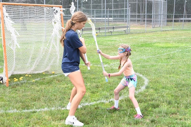 girls teaching younger students lacrosse