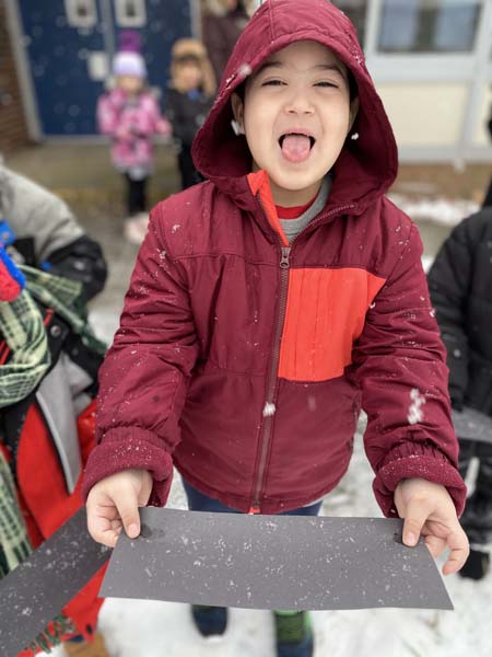 Kindergarten student outside catching snowflakes