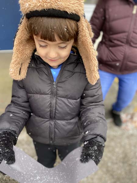 Kindergarten student outside catching snowflakes