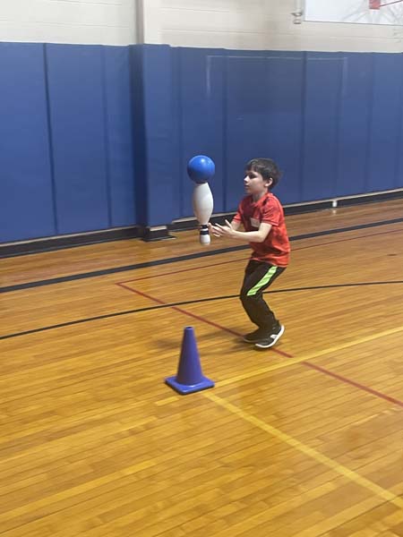 students balancing objects in gym